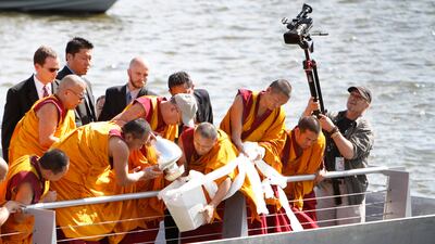 July 16, 2011: The Dalai Lama, center left in baseball cap, pours mandala sand mixed with river water into the Anacostia River as part of a blessing ceremony in Washington. AP Photo/Jacquelyn Martin