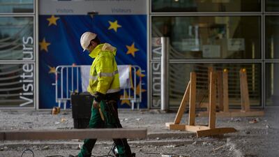 A construction worker stands in front of a door with the EU stars at EU headquarters in Brussels. AP Photo
