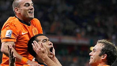 Giovanni van Bronckhorst, centre, the Holland captain, is mobbed by his teammates after his superb strike gave the Dutch the lead against Uruguay last night.