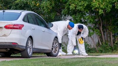 Investigators examine the ground as they search for clues at the scene of a stabbing in Weldon. AP