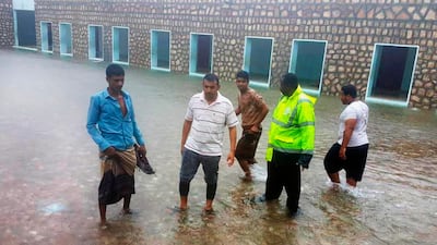 Men stand in floodwater in Hadibu, Socotra.