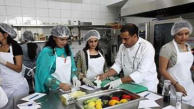 Anjum Memon, left, and Sosan Rameez, centre, attend a cooking class taught by Abderrahim Lhannaoui at the European International College in Abu Dhabi.