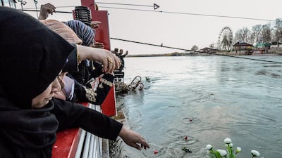Iraqi women cast flowers into the Tigris river in remembrance for the victims of the capsized ferry in the northern Iraqi city of Mosul on March 22, 2019. AFP
