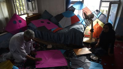 Kite vendor Halim Muhammadi cuts tissue papers as he makes kites with his daughter Nigina in their home in Kabul.