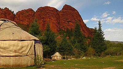 In a valley in eastern kyrgystan, a local woman provides food and lodging for tourists in a cluster of yurts.