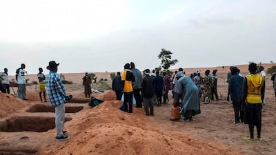Officials and residents stand near freshly dug graves in the Dogon village of Sobane-Kou, near Sangha. AFP