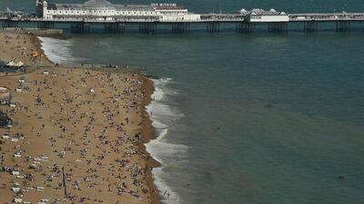 Beachgoers relax by the sea in Brighton, southern England. AFP