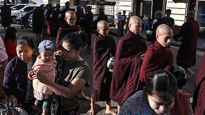 People give alms to Buddhist monks in Yangon, a day before the start of Myanmar's general election. AFP