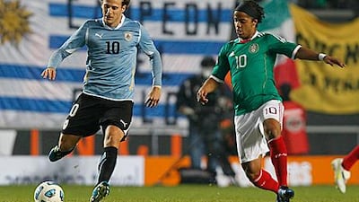 Diego Forlan, left, is put under pressure by Mexico's Giovani Dos Santos during Uruguay's 2-0 win to set up their quarter-final with Argentina at the Copa America.