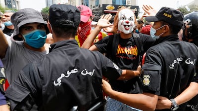 A demonstrator wearing a mask gestures in front of police officers standing guard during the anti-government protest.