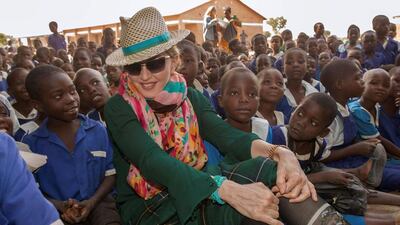 US pop superstar Madonna sits among Malawian children during a visit to the Mkoko Primary School in November 2014. A court in Malawi on February 7, 2017 approved Madonna’s request to adopt two four-year-old twin girls, adding to the two other children that the US pop superstar adopted previously from the country. Amos Gumulira / AFP