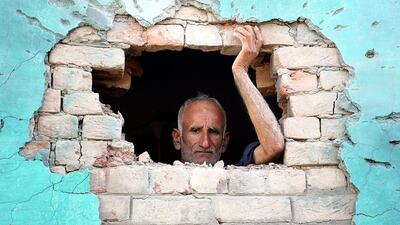 A villager looks from hole in the wall of a building allegedly damaged by shelling from the Pakistani side of the disputed Kashmir border, in Bobiya village of Hiranagar sector, capital of Kashmir. Jaipal Singh / EPA