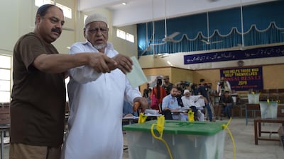 A Pakistani man helps his blind father to casts his vote at a polling station during Pakistan's general election in Islamabad. AFP