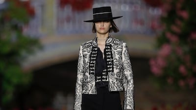 A model wears a patterned jacket, with military-style frogging and a gaucho hat as part of Dior Cruise 2023. AP