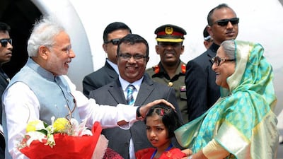 The Indian prime minister Narendra Modi accepts a bouquet from a young girl as he is greeted at the Hazrat Shahjalal International airport in Dhaka by Bangladeshi prime minister Sheikh Hasina at the start of a two-day state visit on June 6, 2015. EPA