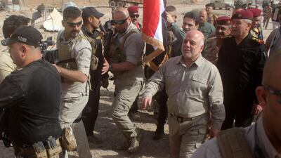 Iraqi prime minister Haider Al Abadi prepares to erect a national flag in A -Qaim on November 5, 2017, after troops retook the border town from ISIL. Moadh Al Dulaimi / AFP