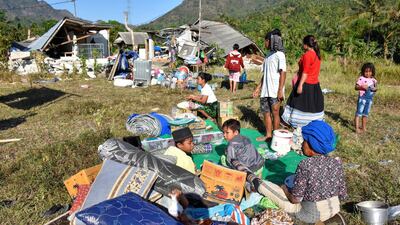 Residents sit outside their home with their belongings following a strong earthquake in Pemenang, North Lombok. Reuters