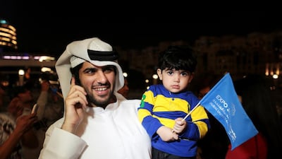 A young bid supporter waves an Expo 2020 flag at the Dubai Mall while his guardian calls a friend to tell them the good news. Christopher Pike / The National