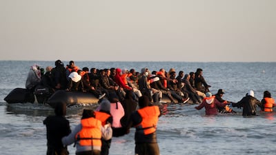 Migrants wade through the sea to board an inflatable dinghy in a bid to cross the English Channel. Reuters