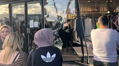 People stand outside the damaged front windows of the shop in the Greenacre. REUTERS