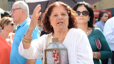 A woman with a candle and photo joins crowds seeking justice for journalist Daphne Caruana Galizia killed when a bomb exploded in her car. (AP Photo/ Rene Rossignaud)