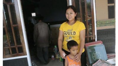 Darsem binti Dawud with her son in front of her new house in Trungtum, West Java. Tatan Syuflana / AP Photo