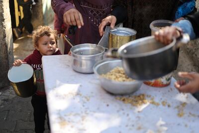 A child waits for a meal at a charity kitchen in Rafah, southern Gaza, amid growing food shortages. Reuters