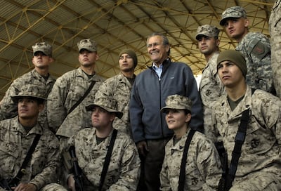 (FILES) In this file photo taken on December 09, 2006 a Photo released by the US Departmet of Defence shows outgoing US Secretary of Defence Donald Rumsfeld posing with troops assigned to Al-Asad Air Base in Iraq's restive Al-Anbar province during a surprise visit to Iraq, 09 December 2006. - Former US defense secretary Donald Rumsfeld, who led the nation into war in Afghanistan and Iraq during the presidency of George W Bush, has died at the age of 88 in New Mexico, his family announced June 30, 2021. (Photo by Cherie A Thurlby / DoD / AFP)