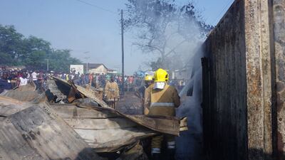 Firefighters spray water onto a burnt container at PMB Wellington Industrial Estate, east of Freetown. AFP