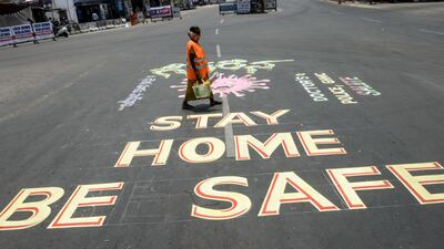 A municipal corporate worker walks past a graffiti drawn at a traffic junction urging people to stay at home during a government-imposed nationwide lockdown in Secunderabad, the twin city of Hyderabad. AFP