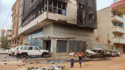 Children walk past the burned-out headquarters of Sudan's Central Bureau of Statistics in southern Khartoum. More than a million people could have fled Sudan by October to escape fighting. AFP