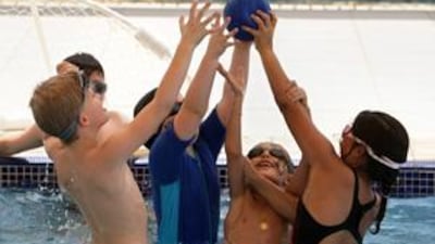 Children play water polo during the swimming class as part of the summer camps which are held at the Al Raha International School. l