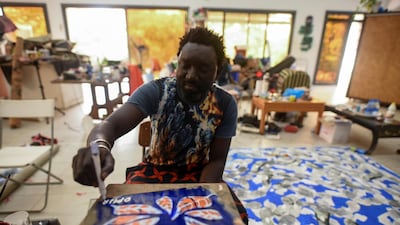 Senegalese artist Omar Ba signs his name on a painting of orange leaves in his studio in Bambilor, Senegal. Cooper Inveen / Reuters