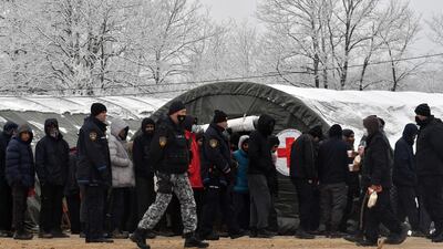 Bosnian police officers watch on as migrants receive food provisions distributed by local Red Cross. AFP