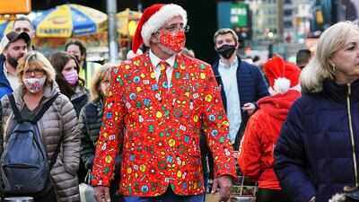 A man wearing a festive jacket, tie and matching mask walks through Times Square in New York. Reuters