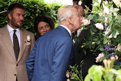 Former England footballer David Beckham, left, and designer Frances Tophill, second left, react as Britain's King Charles III smells a Sir David Beckham Rose. AFP