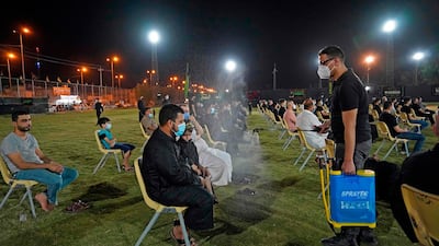 A man sprays Iraqi Shiite Muslims with disinfectant as they gather to commemorate the start of the month of Muharram ahead of Ashura, in the central city of Najaf. AFP