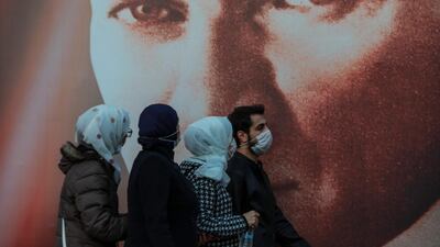 People wearing masks to help protect from the spread of the coronavirus walk past a picture of Mustafa Kemala Ataturk, modern Turkey's founder in Istanbul. AP Photo