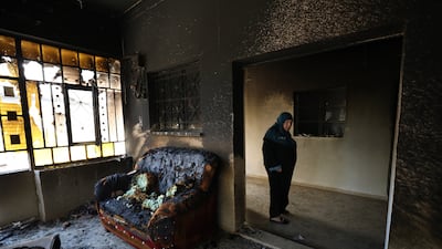 A Palestinian woman stands inside her home in the West Bank village of Tummus Aya that was set on fire by Israeli settlers. EPA