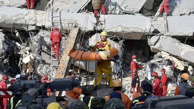 A rescue worker brings down a victim from the collapsed Wei Kuan complex building in Tainan, southern Taiwan, on February 7, 2016, following a strong 6.4-magnitude earthquake that struck early on February 6. Rescuers raced on February 7 to free more than 120 people buried under the rubble of an apartment complex felled by an earthquake in southern Taiwan that left 24 confirmed dead, as an investigation began into the collapse. AFP PHOTO / Sam Yeh