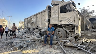 A man sits in front of a lorry damaged in an Israeli attack in Gaza. Getty Images