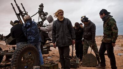 An anti-Qaddafi rebel fighter looks towards the sky for government bombers, as rebel forces reload an anti-aircraft gun near Ras Lanuf yesterday.