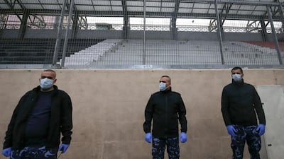 Members of the Palestinian security forces wearing protective masks stand guard during a football match without fans, amid fears of the spread of the novel coronavirus, in the West Bank city of Hebron. AFP
