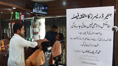 Pakistani hairdressers work at their stations beside a notice sign of the the Sulemani Hairdressers Association that reads "All hairdressers by unanimous decision have decided not to offer their services for clients wishing for stylish beards. It is an insult of Sunnah of Prophet. Violators will be given a harsh punishment". Abdul Majeed / AFP