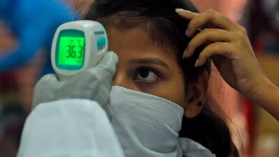 A medical volunteer takes temperature reading of a woman at a coronavirus testing centre in Mumbai on July 17, 2020. AFP