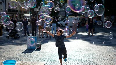 A child chasing soap bubbles made by a street artist in Lisbon's downtown Rossio Square. AP Photo
