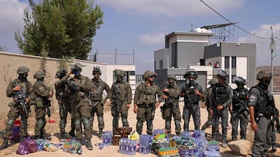 Israeli soldiers stand in front of a Palestinian house besieged by settlers in Qusra, with supplies left for the residents by activists. AFP