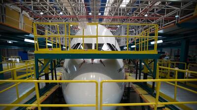A front shot of the aircraft nose with the plane in a hangar with platforms on either side during a C-check.