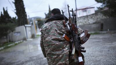 An ethnic Armenian fighter carries Kalashnikov machine guns to his comrade-in-arms at Martakert province in the separatist region of Nagorno-Karabakh, Azerbaijan. Fighting entered a fourth day ahead of talks in Vienna. Vahan Stepanyan / PAN Photo via AP