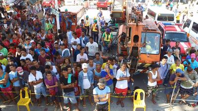 Residents look on as search operations continue at a collapsed commercial building in Porac town. EPA